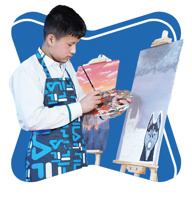 A boy in an art apron painting on a canvas in a classroom setting.