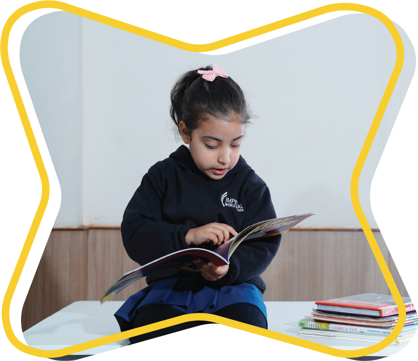 A young girl sitting and reading a book attentively, surrounded by school supplies.
